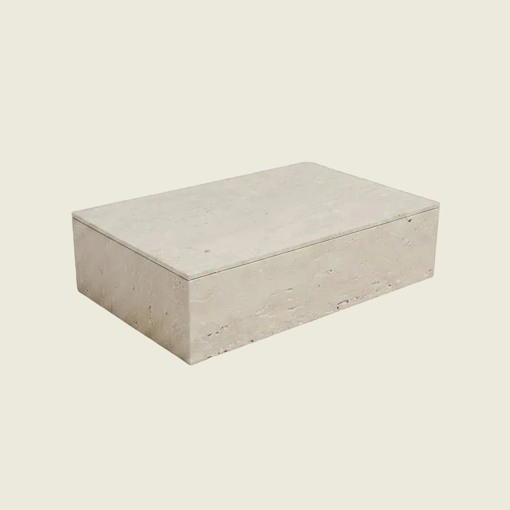 A rectangular travertine stone block or tile sample in a light beige color, shown at an angle against a solid black background.